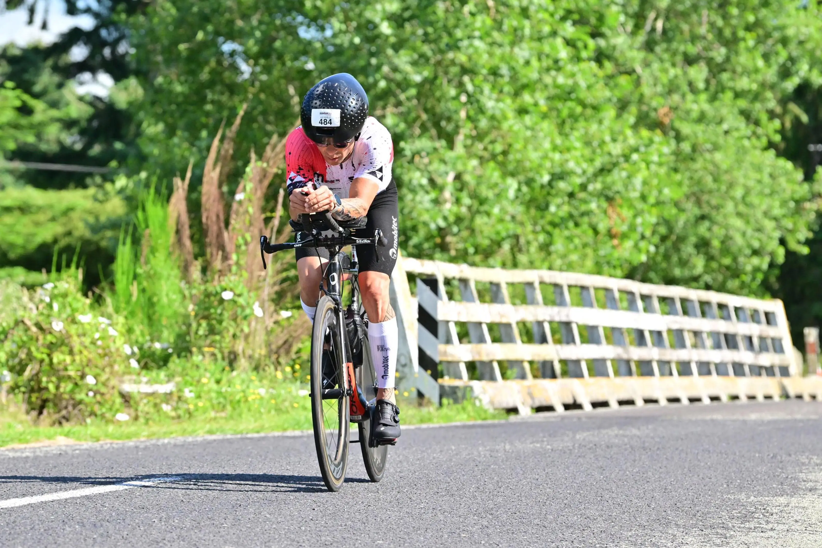 Hermes pedalando ao lado de uma ponte de madeira